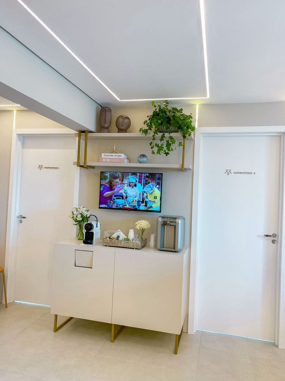 Cantinho do café com TV entre as portas dos consultórios 1 e 2